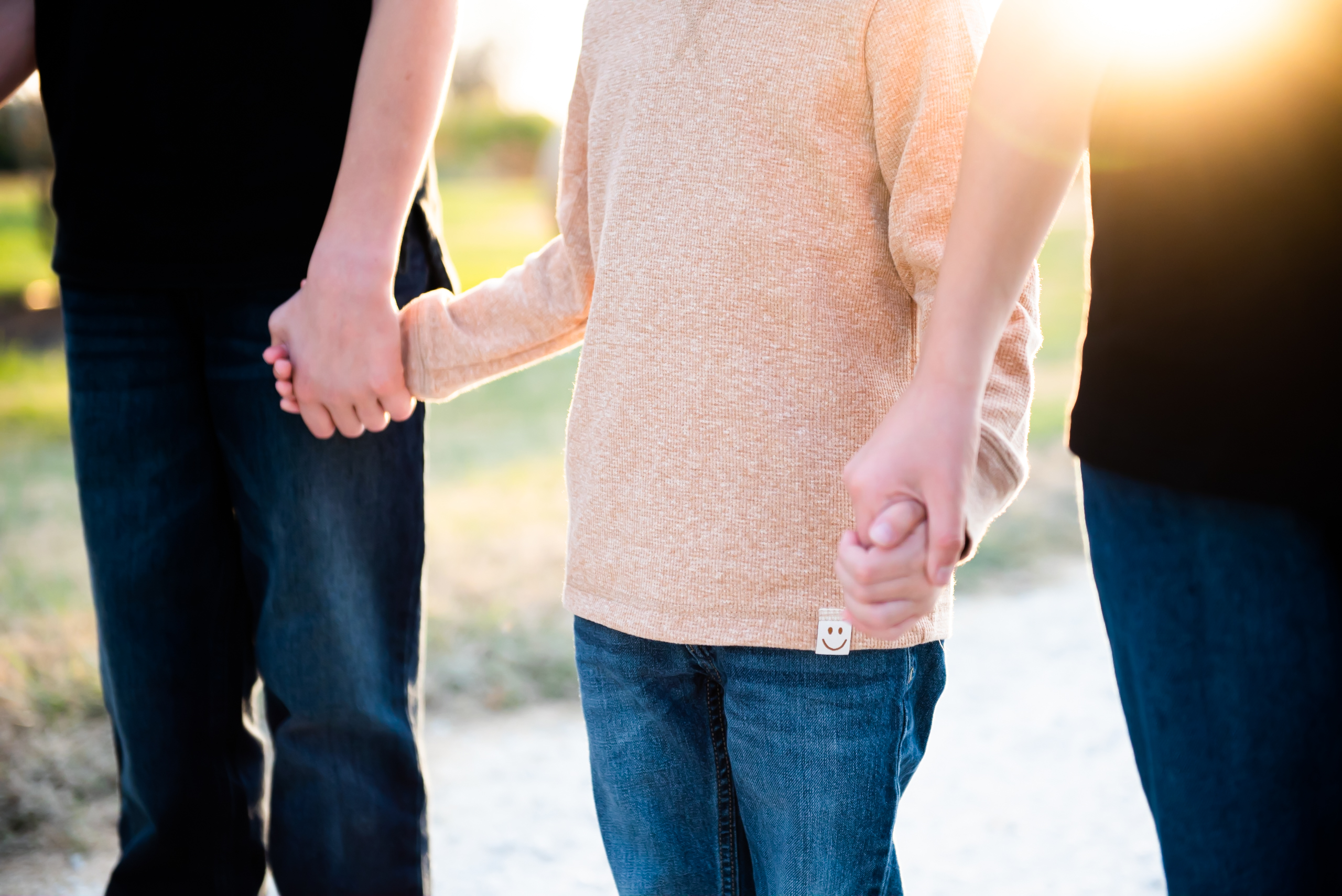 a child between parents, holding their hands. You only see neck down.